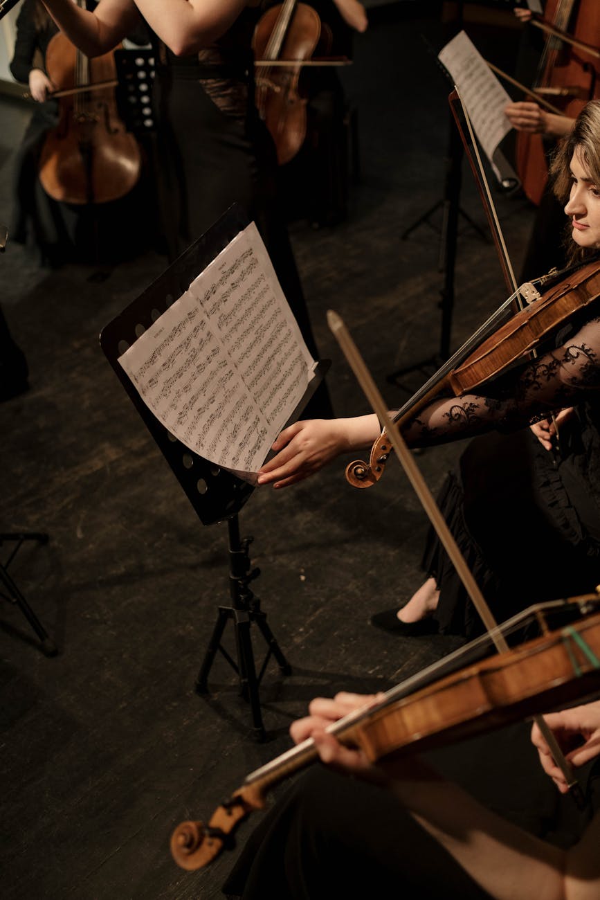 A high-angle view of orchestra musicians performing with sheet music on stage.