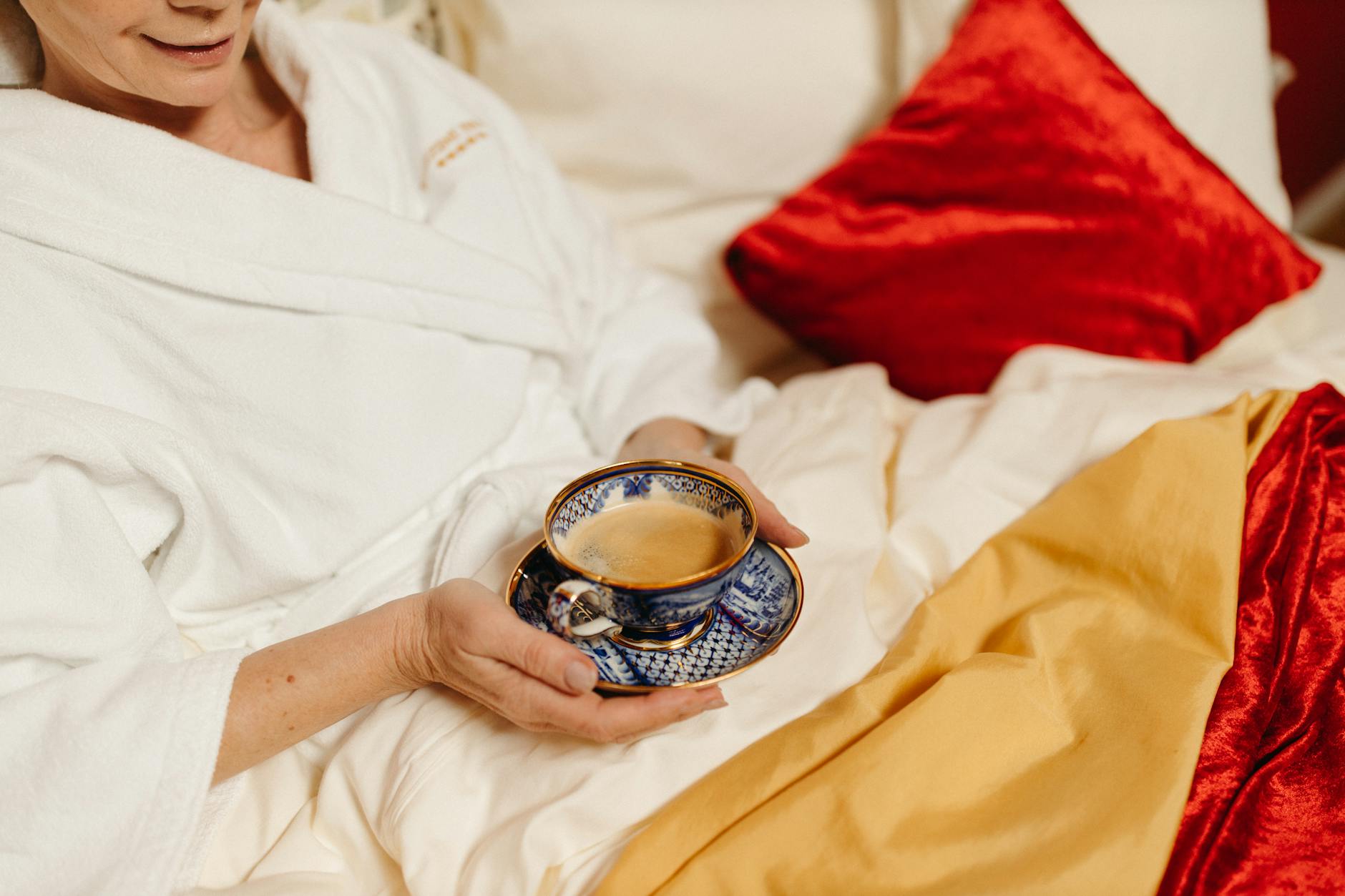 Relaxing morning in bed with a cup of coffee, wearing a bathrobe.