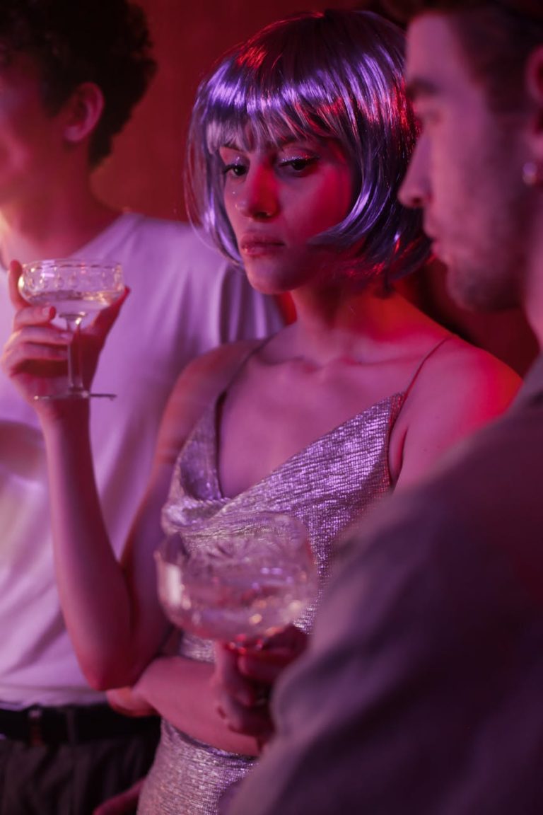 Group of adults enjoying a lively party with neon lighting and stylish wigs.