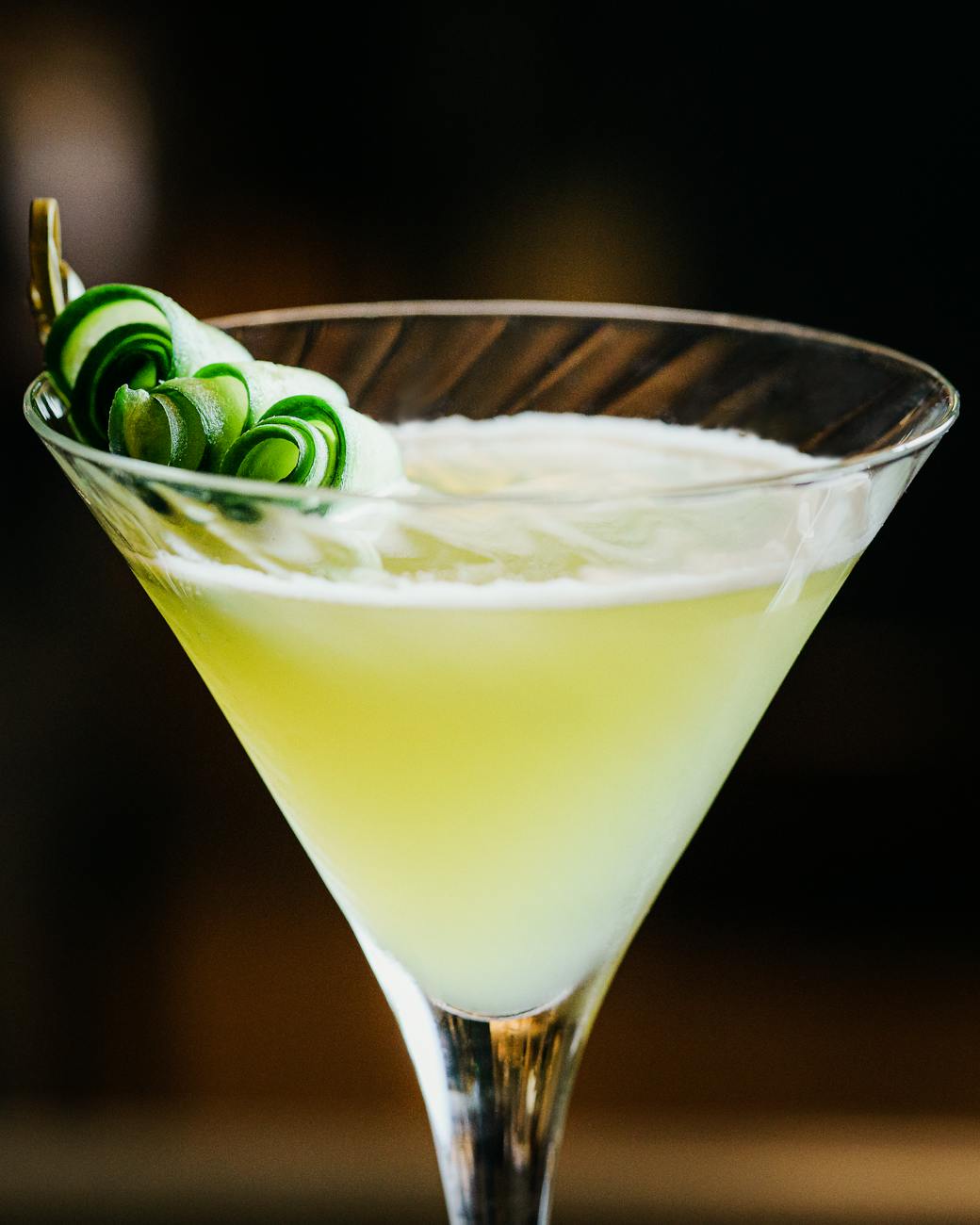 Close-up of a refreshing gin cocktail with cucumber garnish in a martini glass.
