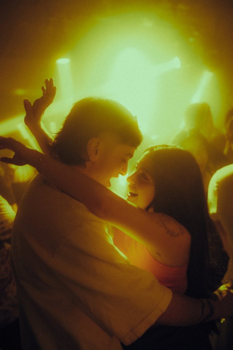 A couple lovingly embraces under vivid lights at a lively club scene in Chile.
