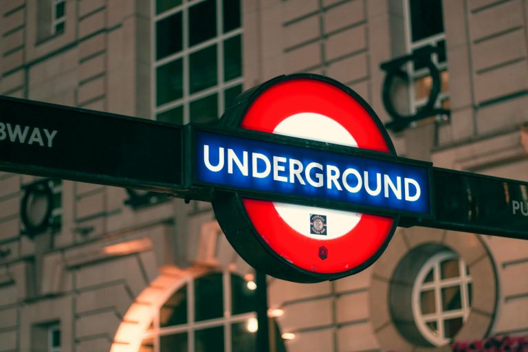 Close-up of the London Underground sign illuminated at night, highlighting a famous transport symbol.