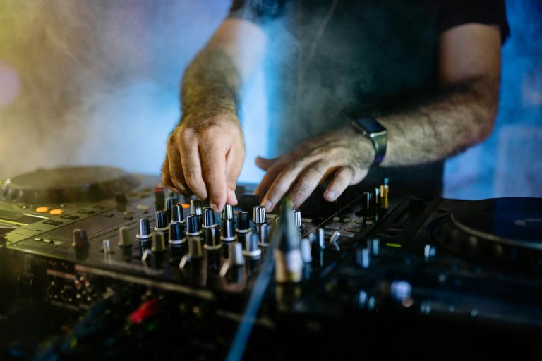 DJ mixing music on an audio mixer with vibrant club lighting and smoke effects.