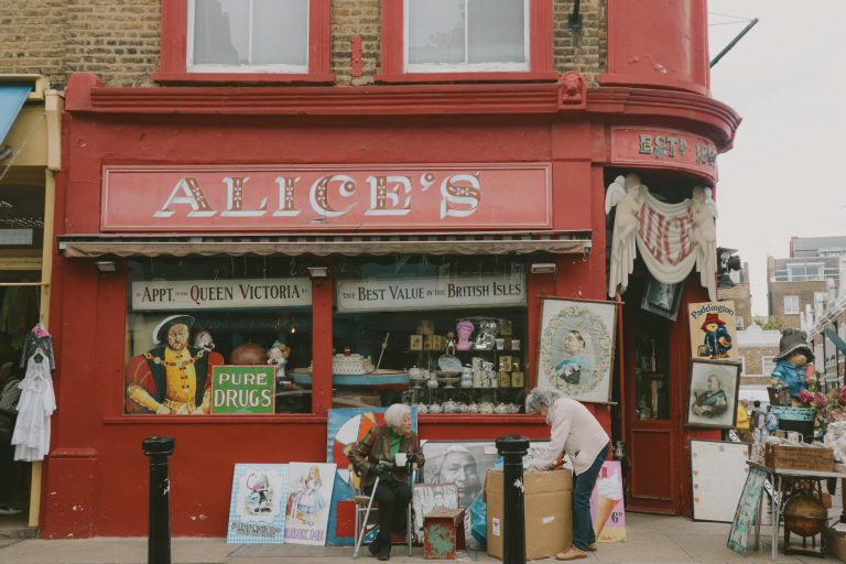 Historic vintage storefront in Notting Hill with vibrant red facade and assorted antiques displayed.