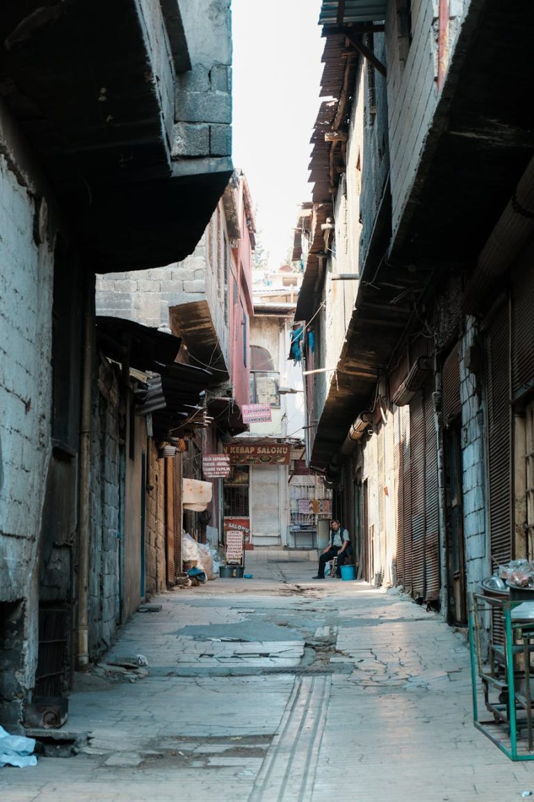 A narrow stone alleyway between aged buildings, capturing urban life and history.