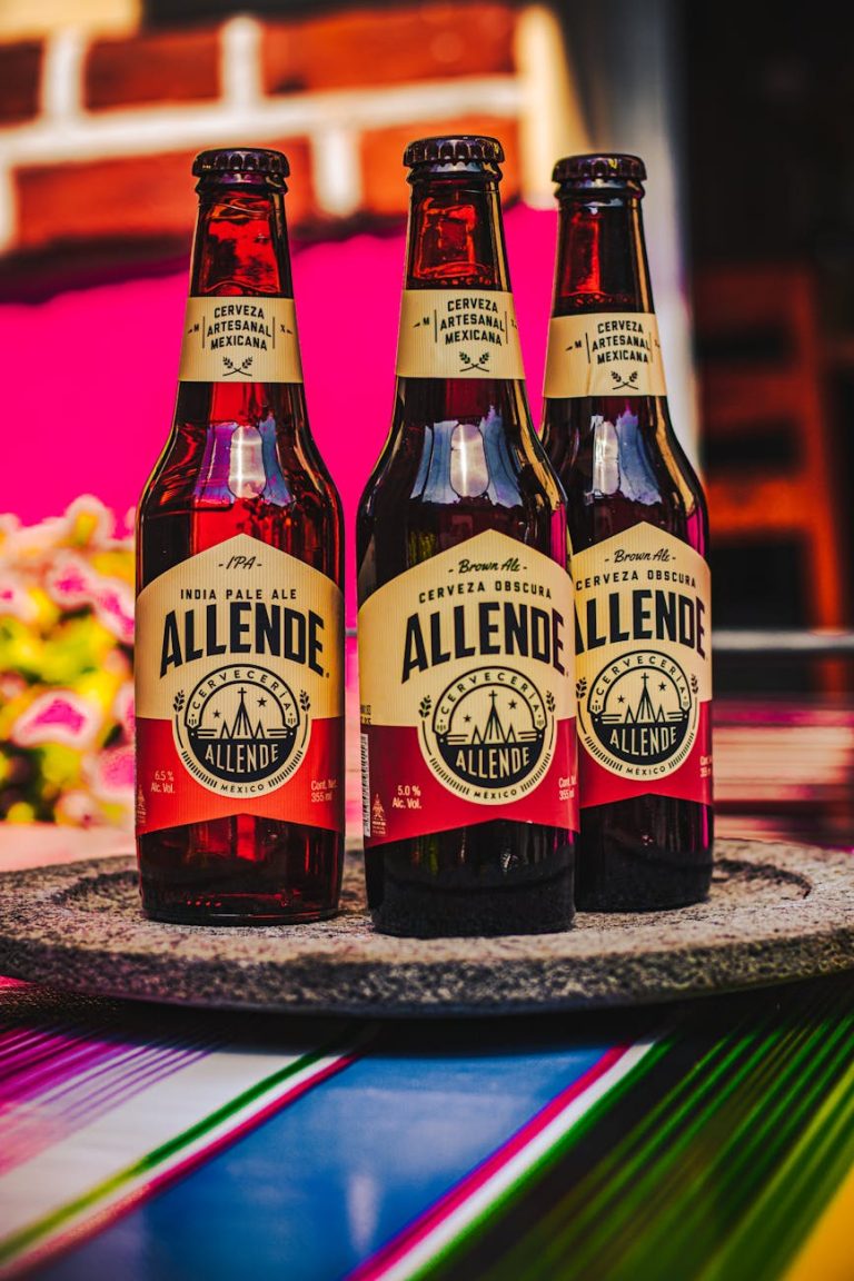 Three Allende IPA bottles arranged on a colorful table setting, showcasing Mexican craftsmanship.