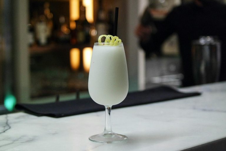 A refreshing white cocktail garnished with a twist, perfect for a night out.