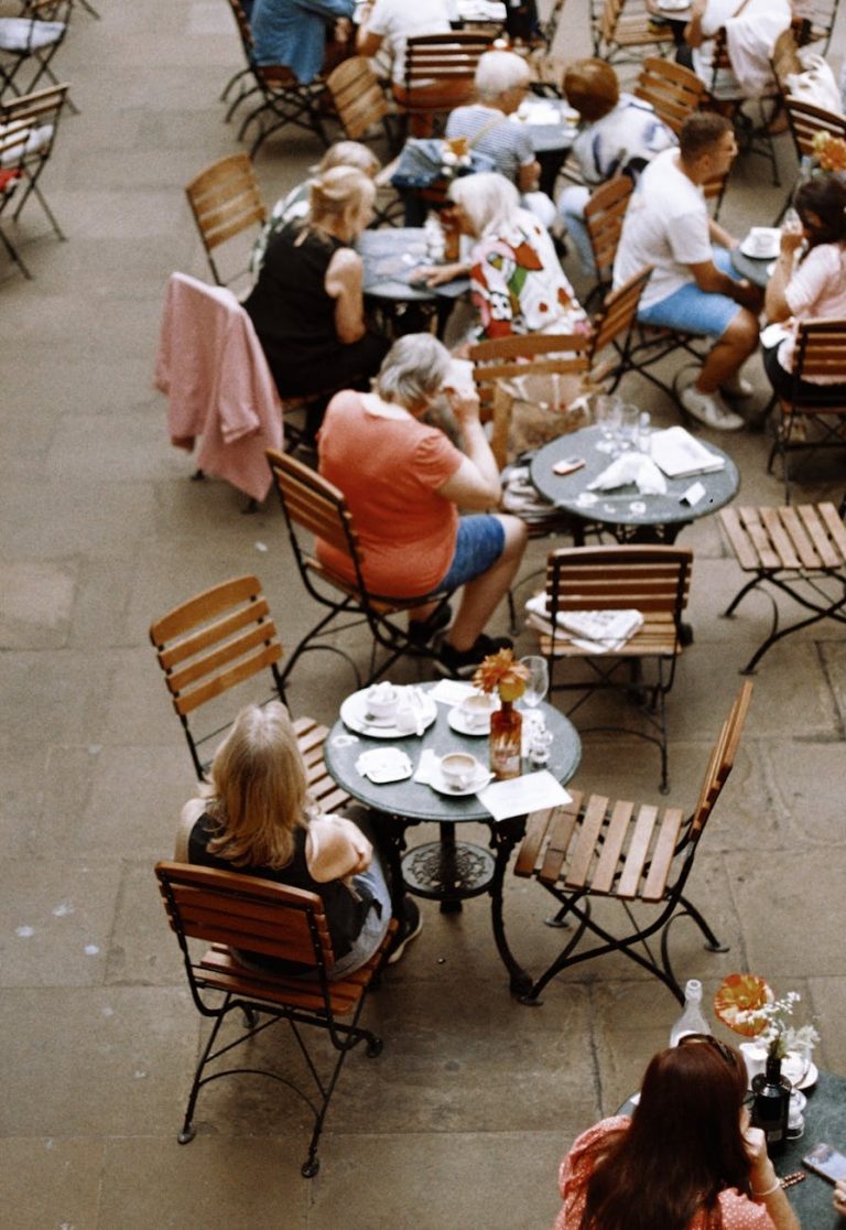 Aerial view of people dining outdoors in a charming London courtyard with wooden tables and chairs.
