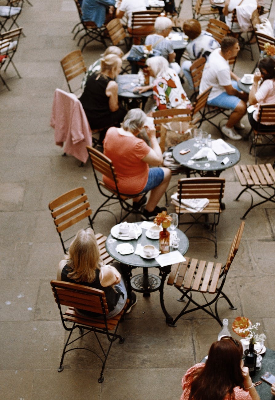 Aerial view of people dining outdoors in a charming London courtyard with wooden tables and chairs.
