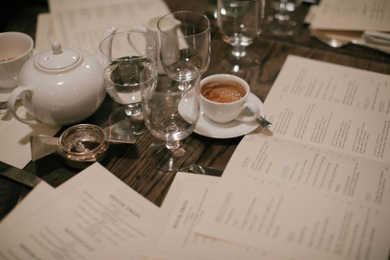 A sophisticated coffee and tea setup with menus and glassware, perfect for a refined gathering.