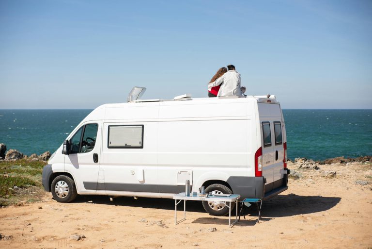 Romantic couple sitting on camper van roof, enjoying ocean view in Portugal.