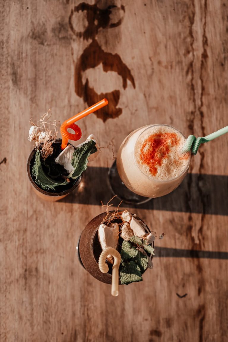 Top view of artistic cocktails with vibrant straws on a rustic wooden table in Angola.