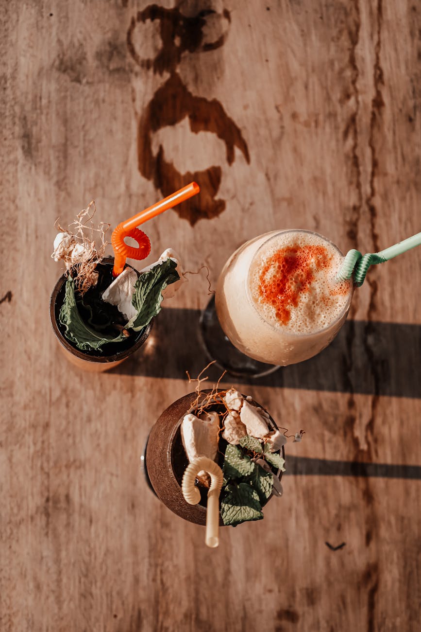 Top view of artistic cocktails with vibrant straws on a rustic wooden table in Angola.