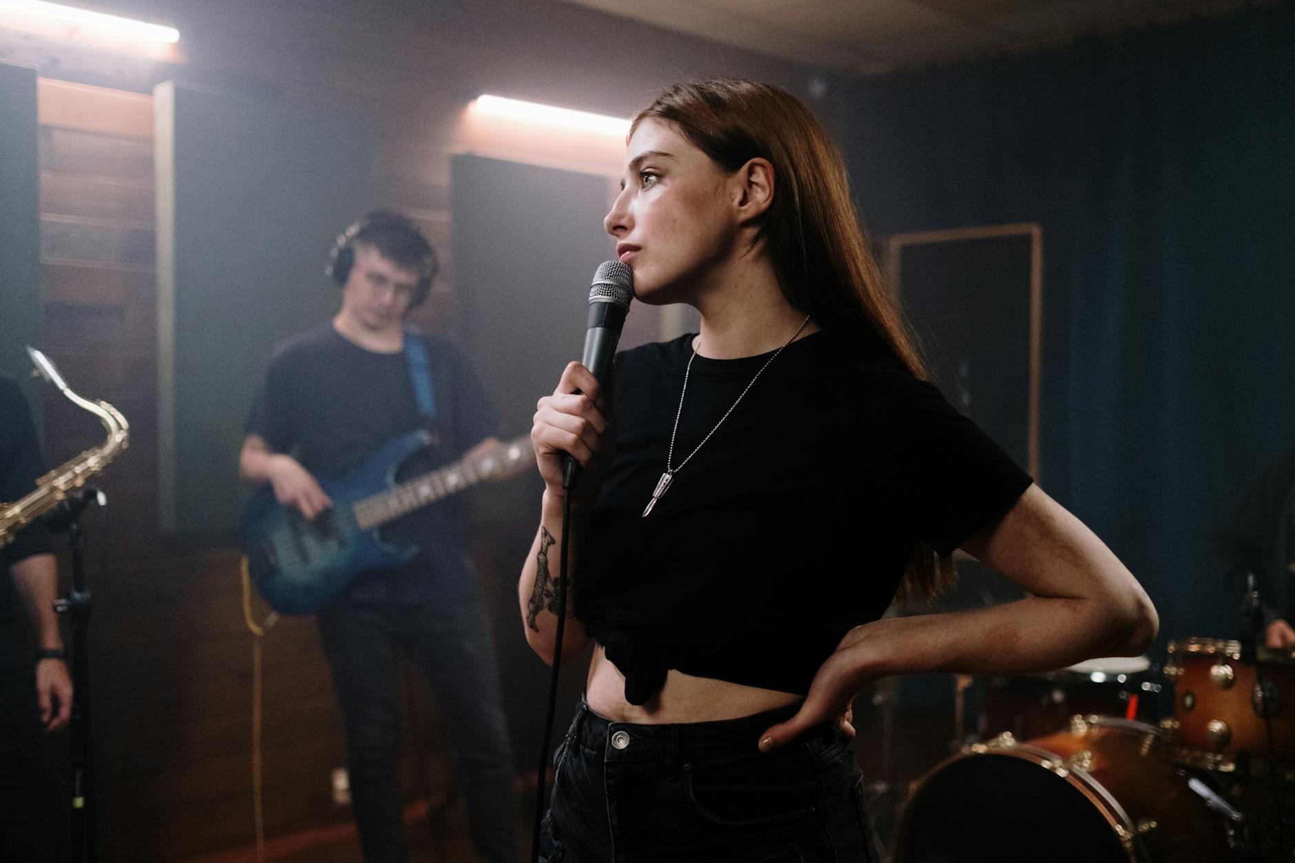 Female singer with microphone in dynamic band performance scene indoors, showcasing live music energy.
