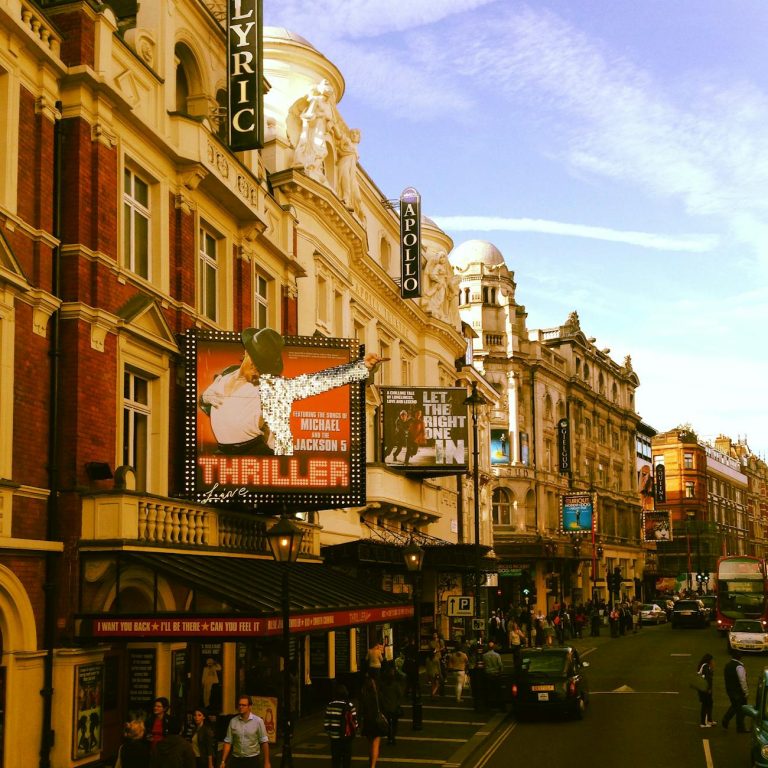 Street view of London's West End showcasing theatres and vibrant urban life.