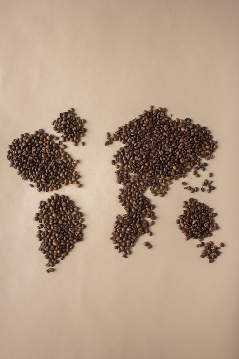 Creative flatlay of coffee beans forming a world map on beige background.