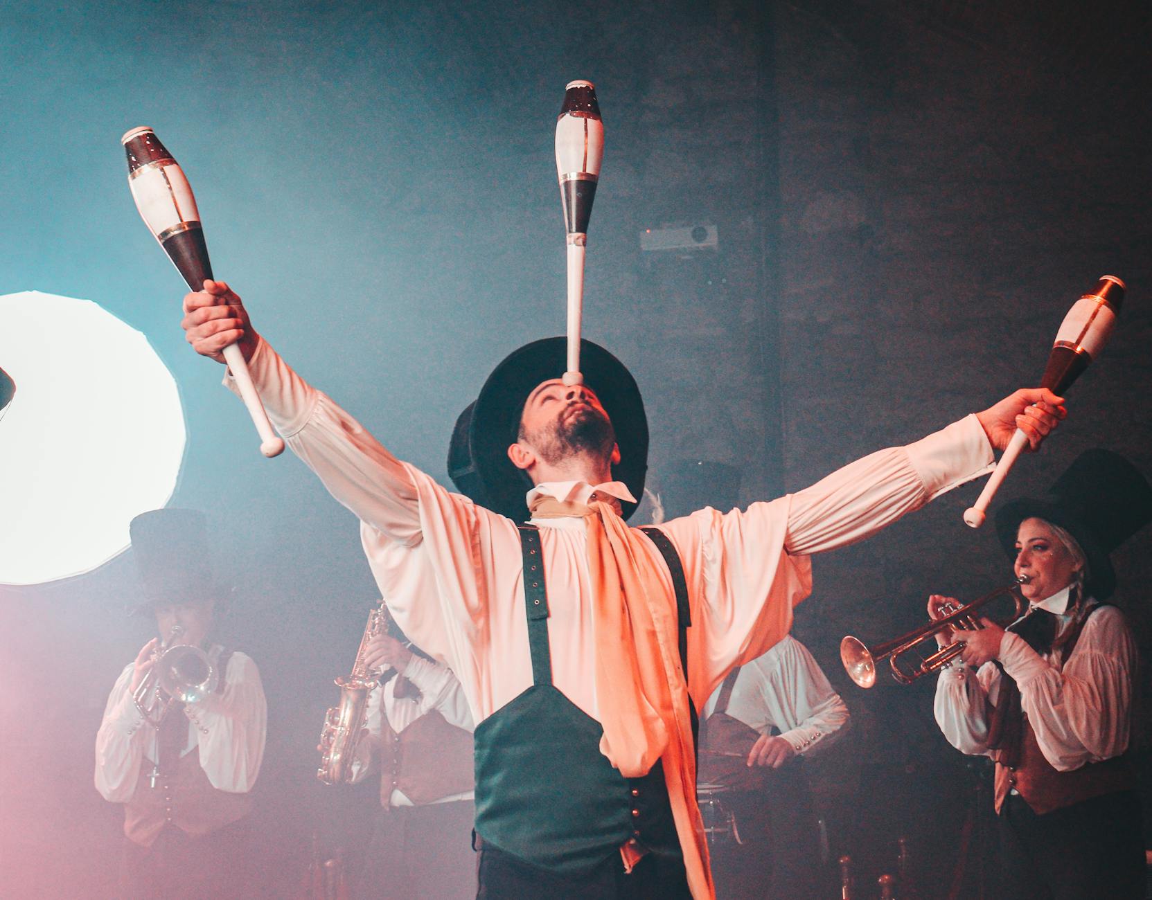 Energetic circus performer juggling clubs in a lively, theatrical setting.