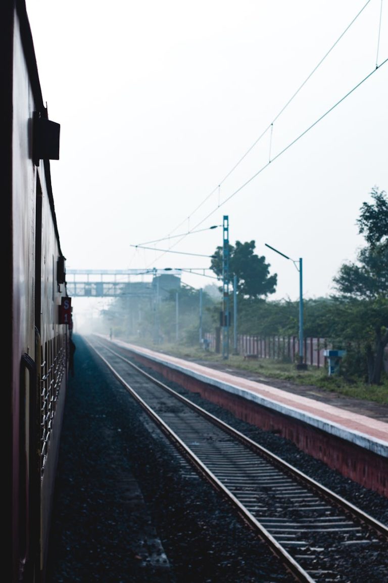 A train traveling on a foggy morning with visible railway tracks and power lines.