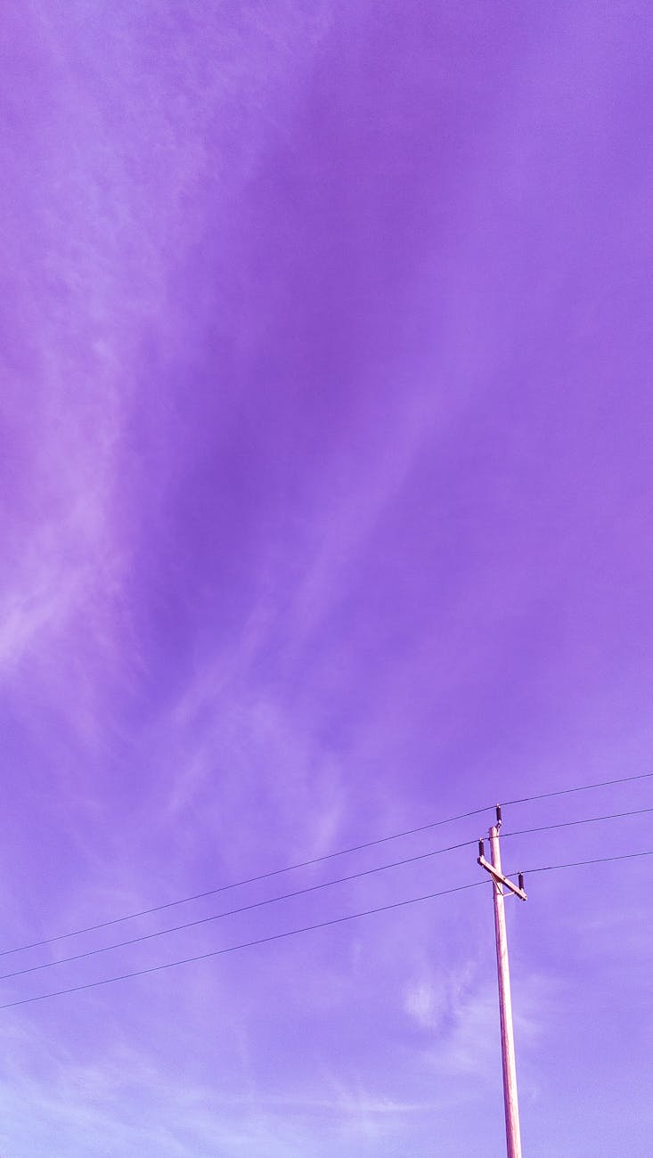 Vibrant purple sky with wispy clouds and a utility pole captured in a vertical shot.