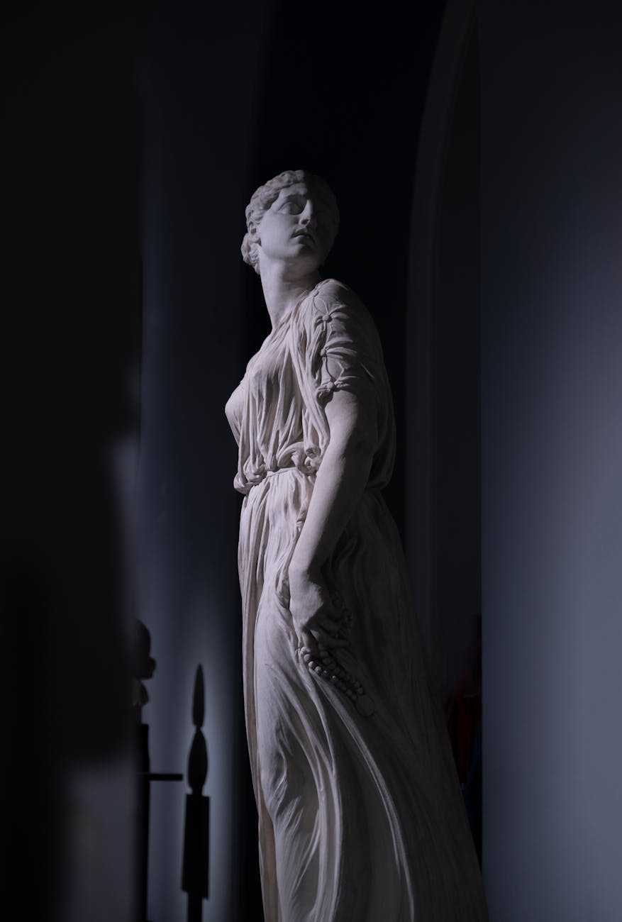 Neo-Classical statue of a Greek goddess with elegant drapery in a shadowy interior.