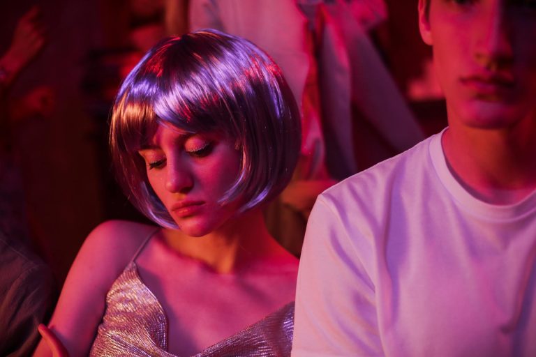 A young couple enjoying a neon-lit party with vibrant lights.