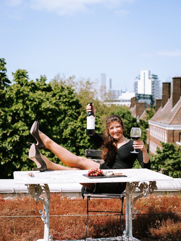 Young woman enjoying wine on a London rooftop, surrounded by urban scenery. Perfect for lifestyle themes.