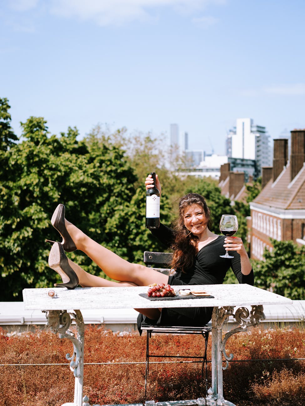 Young woman enjoying wine on a London rooftop, surrounded by urban scenery. Perfect for lifestyle themes.