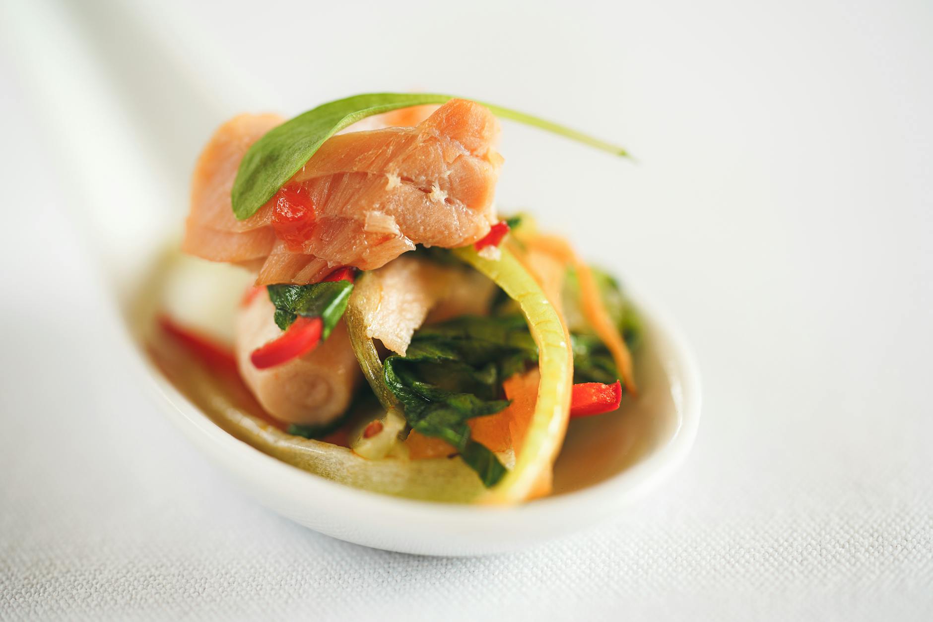 Close-up of a gourmet salmon appetizer with vegetables served in a spoon, shot in London.