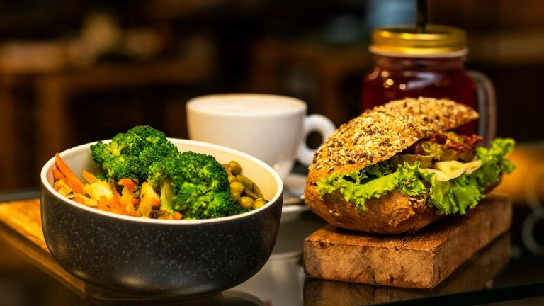 Delicious vegan meal featuring a vegetable sandwich and broccoli salad with a cup of tea.