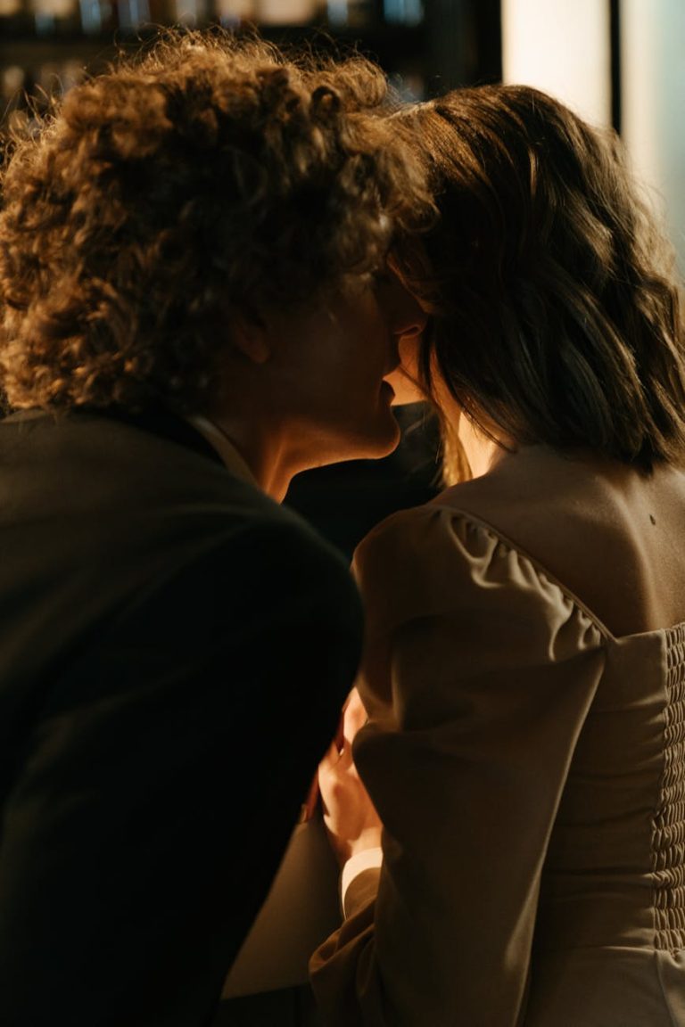A couple shares a tender moment whispering at an elegant bar setting, capturing intimacy and romance.