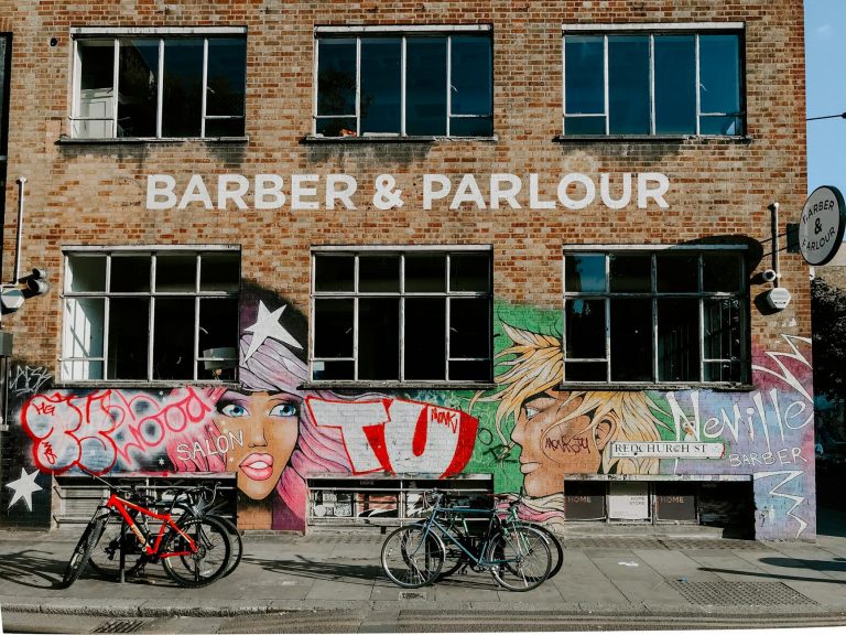 An urban scene of a barber shop with colorful graffiti art and parked bicycles in London.
